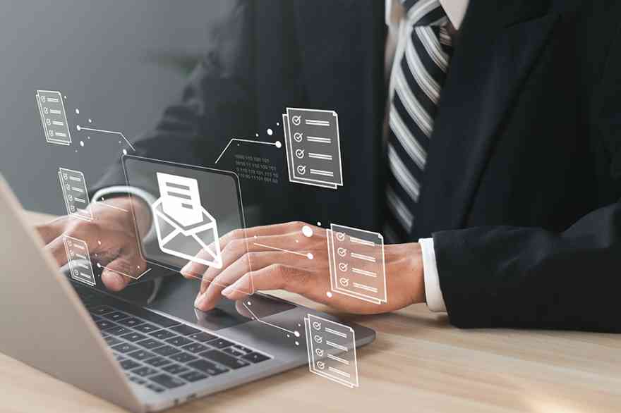 Foto: Mann vor Laptop mit schwebendem digitalen Brief über der Tastatur