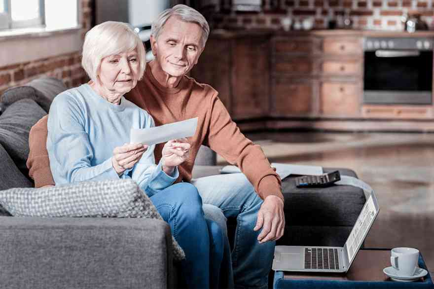 Foto: Älteres Ehepaar auf Couch betrachtet Brief