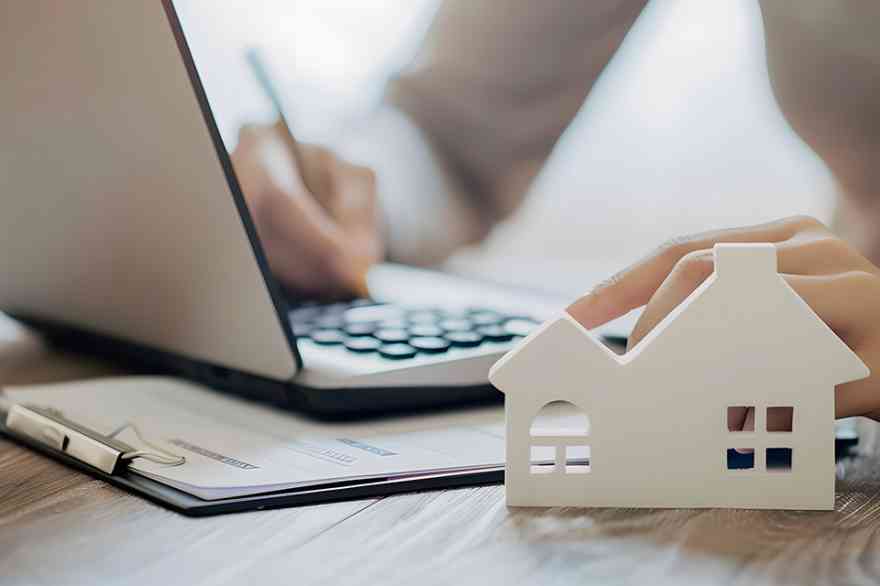 Foto: Person bearbeitet Akten, Modell eines Hauses im Vordergrund